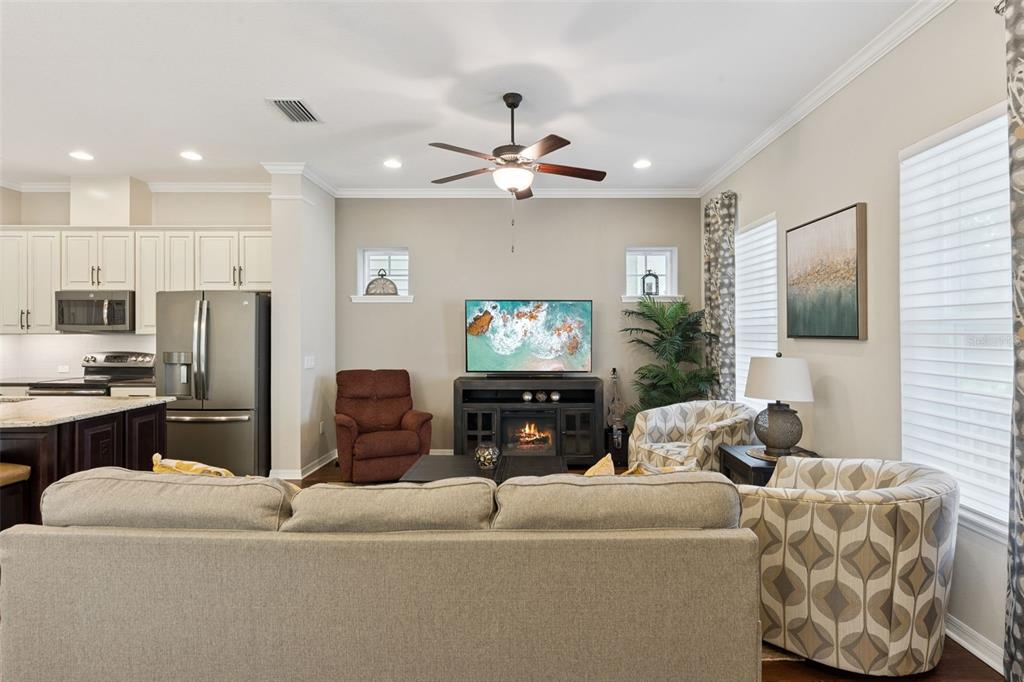 A living room with a gray sofa, patterned armchairs, a television, and an open kitchen — 1425 RESOLUTE STREET, CELEBRATION, FL