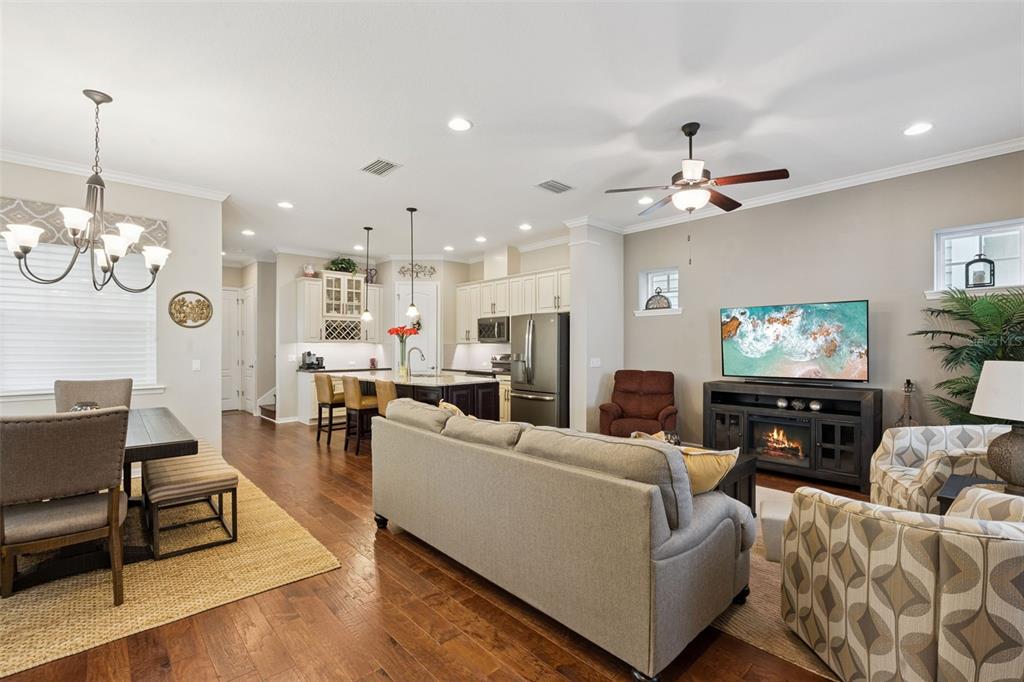 An open-concept living and dining area features hardwood floors, a kitchen island, and a fireplace — 1425 RESOLUTE STREET, CELEBRATION, FL