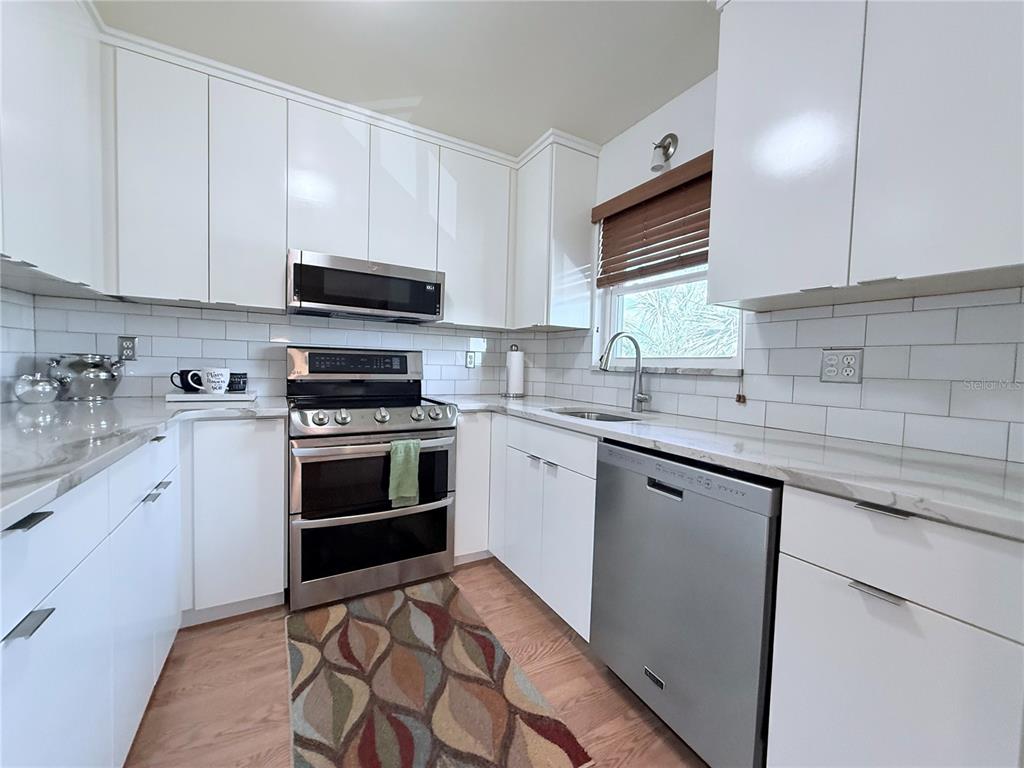 A kitchen features white cabinets, stainless steel appliances, subway tile backsplash, and wood-look flooring — 4460 IRONWOOD CIRCLE UNIT 304A, BRADENTON, FL
