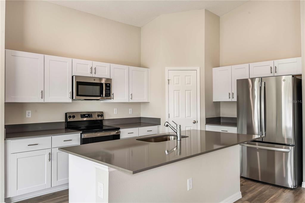 A kitchen with white cabinets, stainless steel appliances, a center island, and gray countertops — 5848 HEAVEN ROAD, HAINES CITY, FL