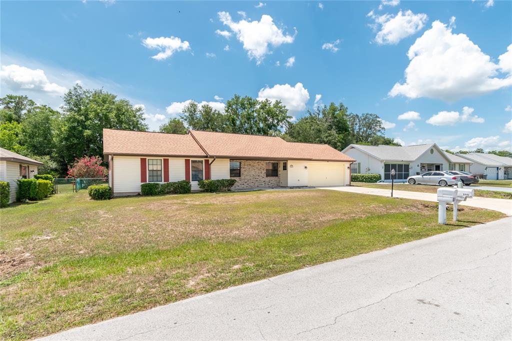 A single-story house with beige siding, a brick facade, and a two-car garage — 3340 NW 44TH COURT, OCALA, FL