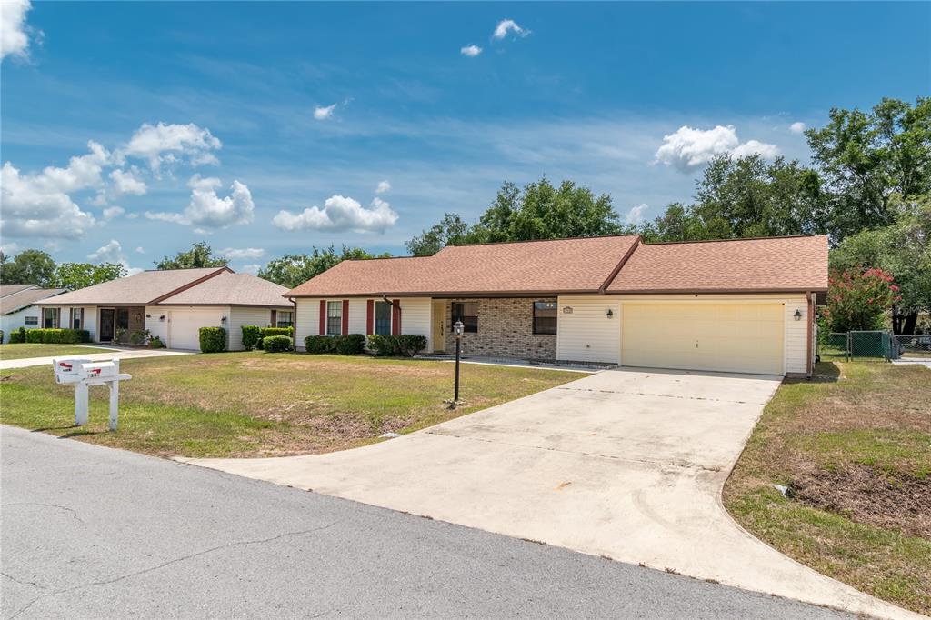 A single-story house with a beige facade, brick accent, and a two-car garage — 3340 NW 44TH COURT, OCALA, FL