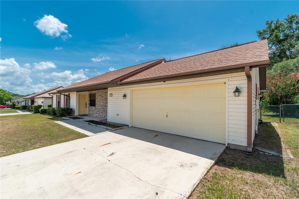 A single-story house with a beige garage door, light siding, and a brown shingled roof — 3340 NW 44TH COURT, OCALA, FL