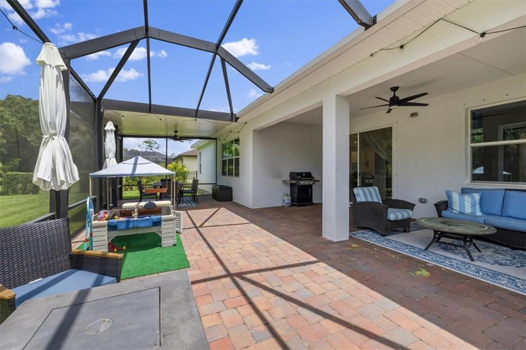 A screened-in patio features brick pavers, outdoor furniture, a grill, and a children's play area — VERO BEACH, FL
