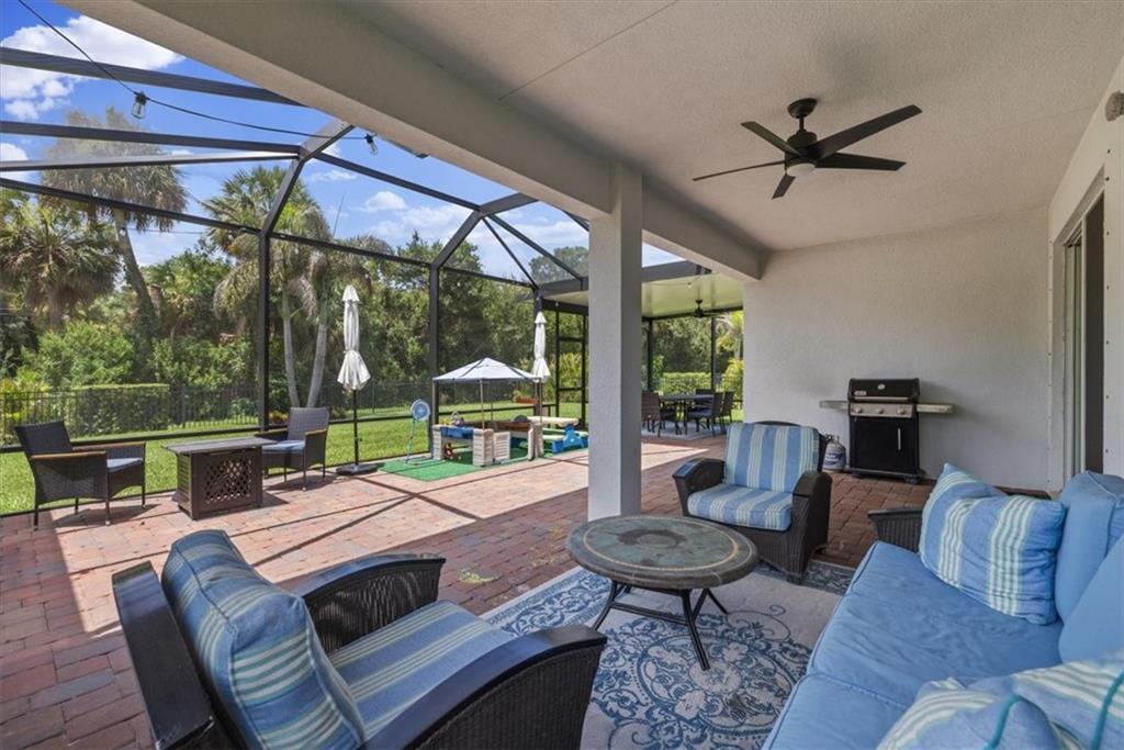 A covered brick patio features outdoor furniture, a ceiling fan, and a screened-in backyard view — VERO BEACH, FL