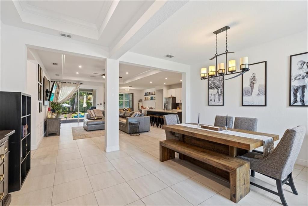 An open-concept dining area with a wooden table and bench leads into a living room — VERO BEACH, FL