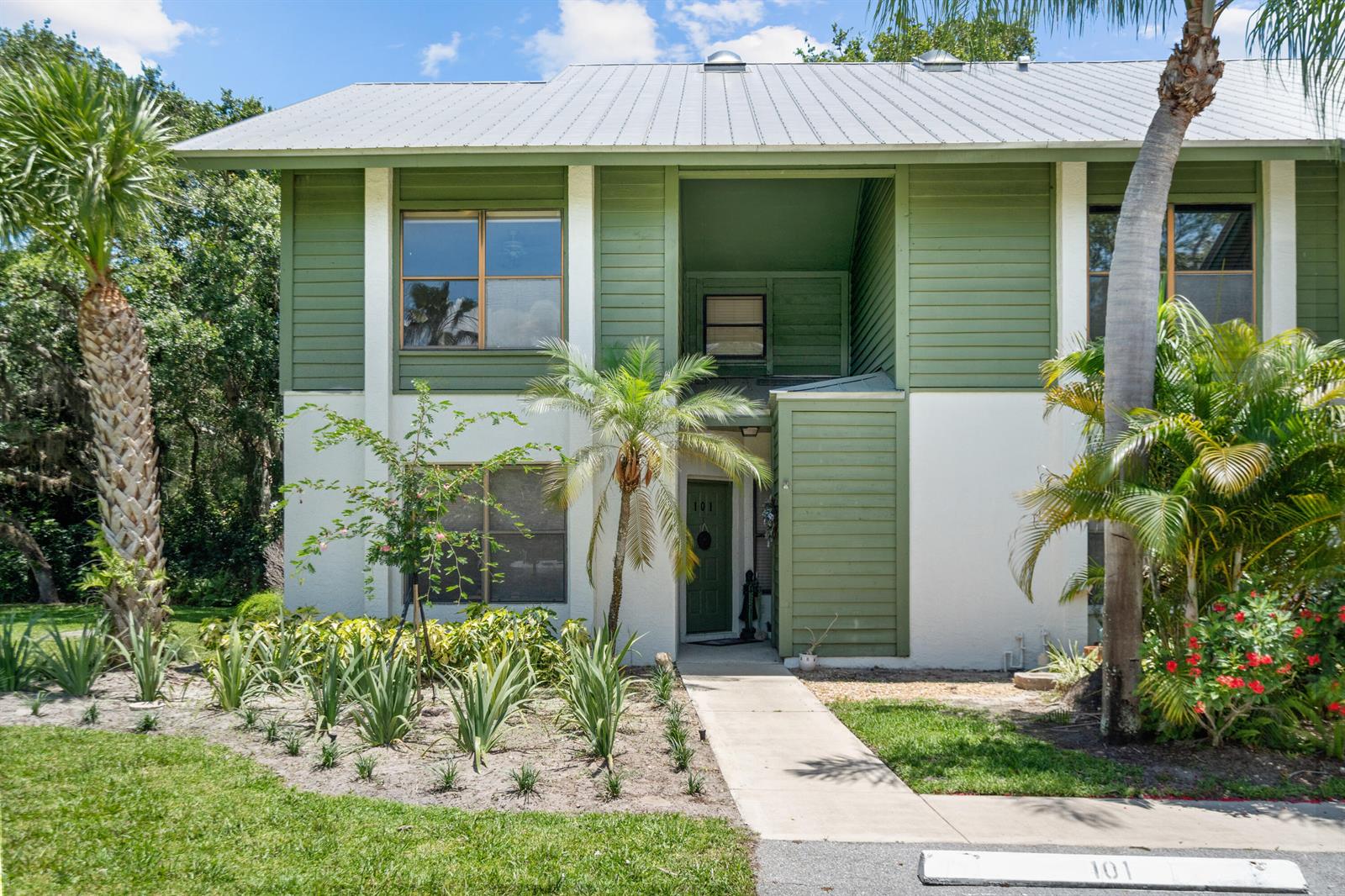 A two-story building with green horizontal siding, white stucco walls, and a metal roof — 5280 SE Seascape Way # 101, Stuart FL 34997, STUART, FL