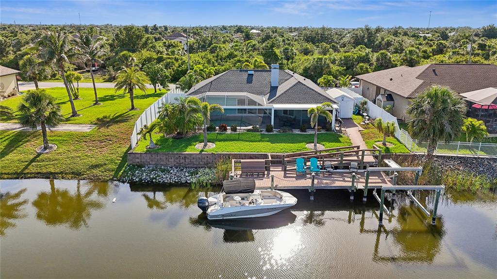 An aerial view of a waterfront house with a screened pool, dock, and motorboat — 10264 WINNIPEG STREET, PORT CHARLOTTE, FL