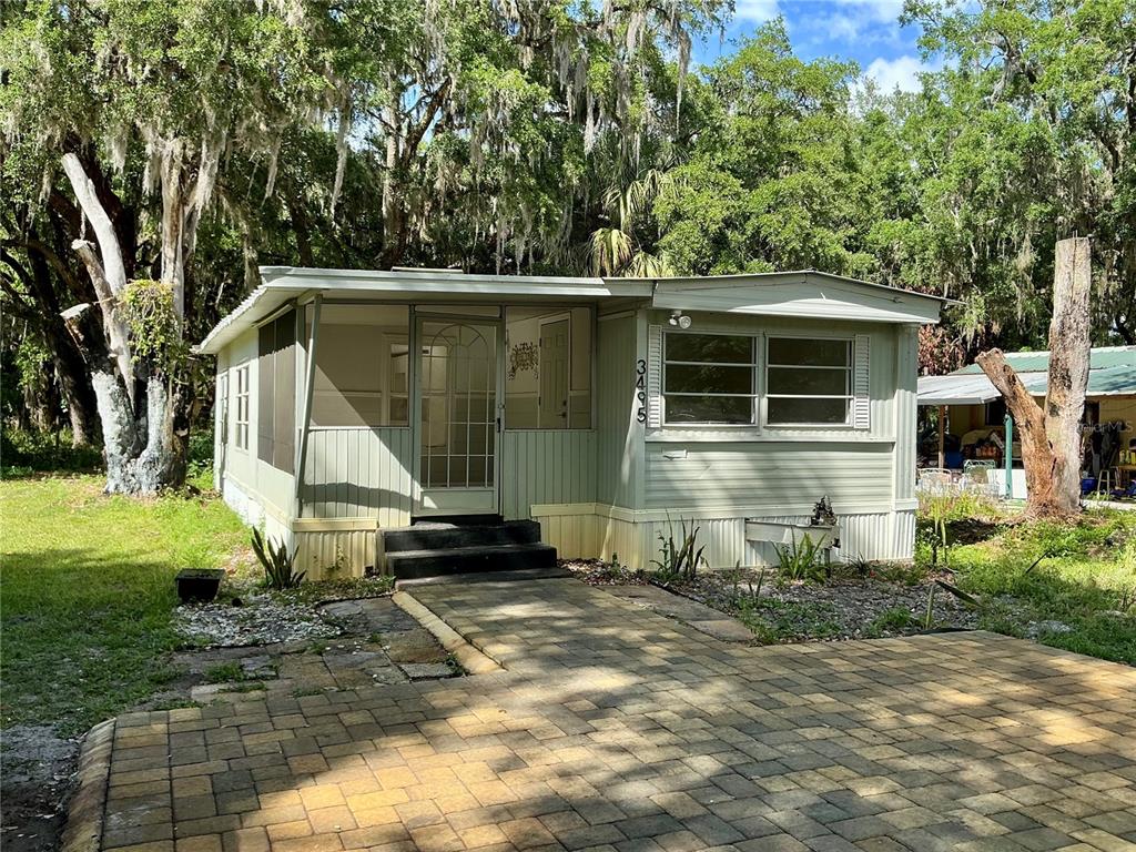 A light green manufactured home features a screened-in porch and a paved stone driveway — 3495 FOREST DRIVE, KISSIMMEE, FL