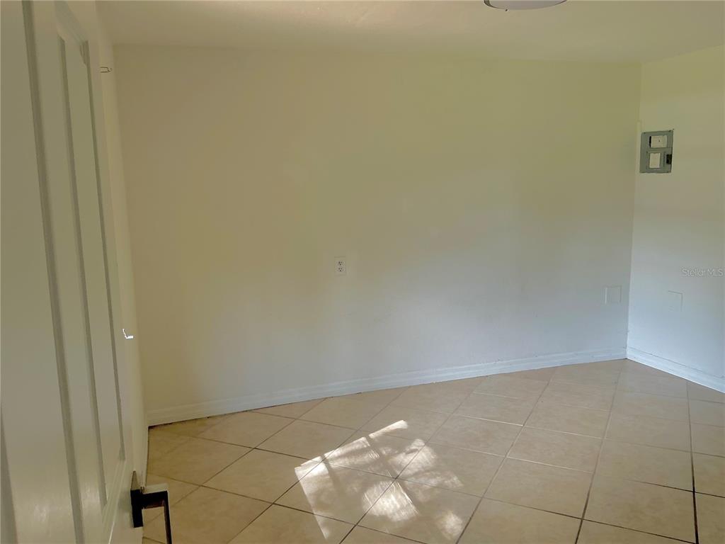 An empty room with light-colored walls, beige tile flooring, and a small electrical panel — 3495 FOREST DRIVE, KISSIMMEE, FL