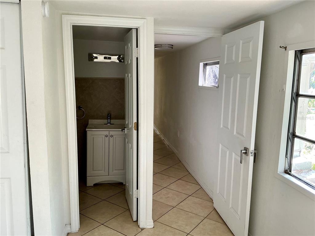 A hallway with tiled floors leads to a bathroom with a white vanity — 3495 FOREST DRIVE, KISSIMMEE, FL
