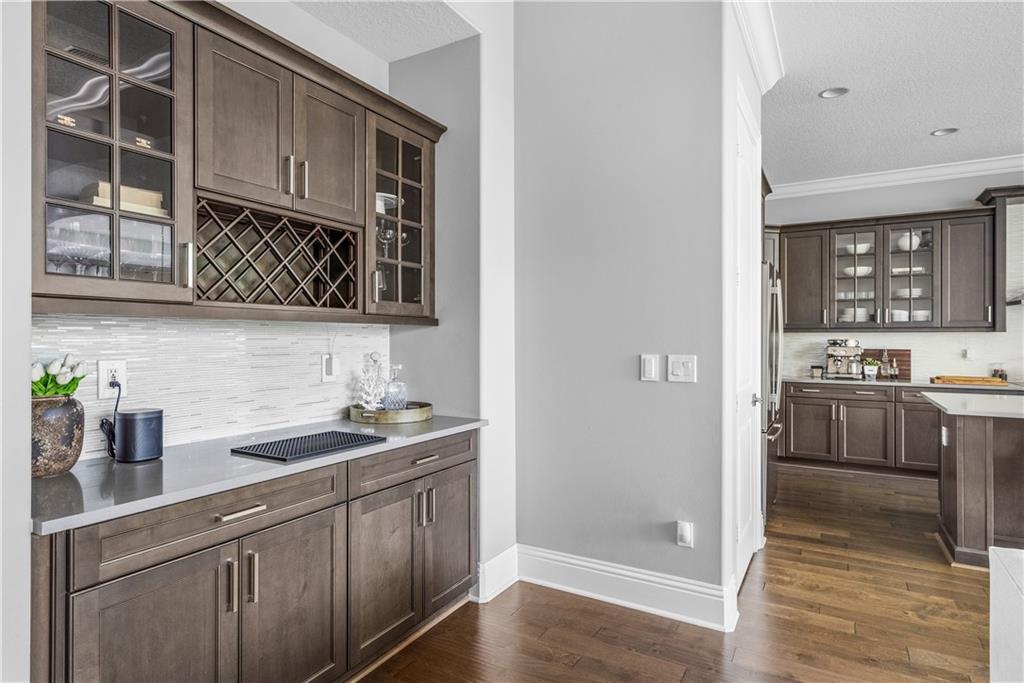 A kitchen and wet bar area featuring dark wood cabinets, gray countertops, and tile backsplashes — VERO BEACH, FL