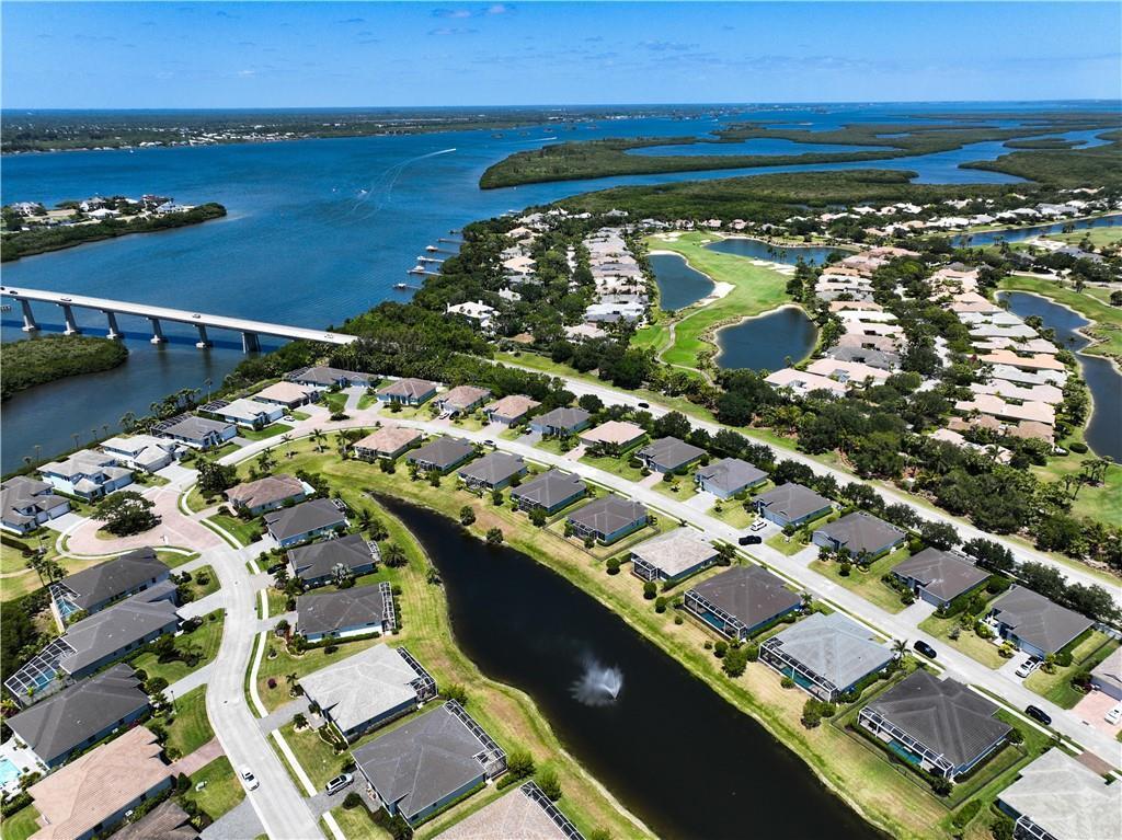 Aerial view of a residential neighborhood with a pond, golf course, and bridge nearby — VERO BEACH, FL