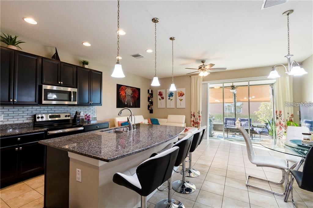 A kitchen with dark cabinets, granite countertops, and an island with bar stools — 6959 TOWNE LAKE ROAD, RIVERVIEW, FL