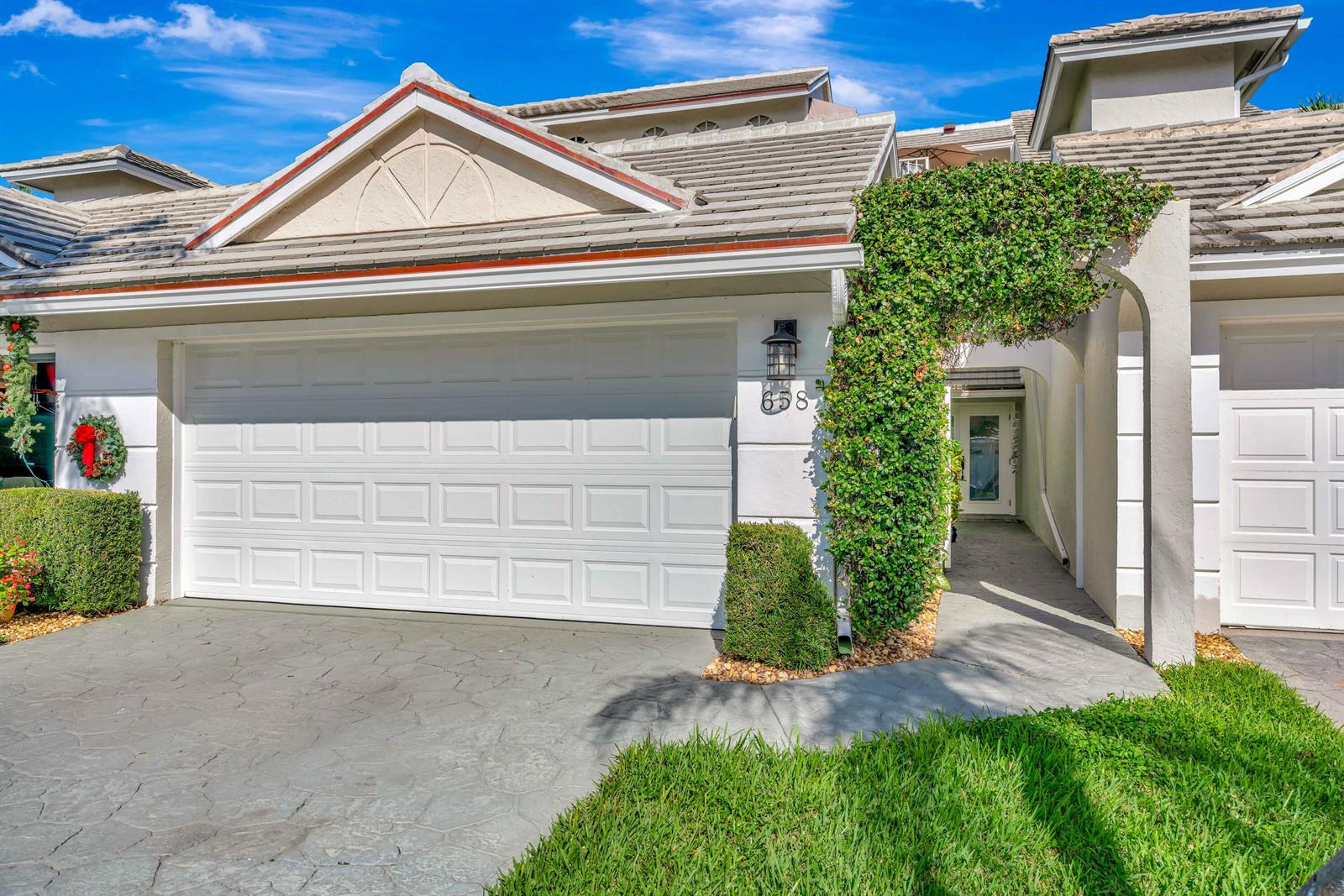 A white garage door and a vine-covered entryway are visible on this residential home exterior — 1000 N Us Highway 1 # 658, Jupiter FL 33477, JUPITER, FL