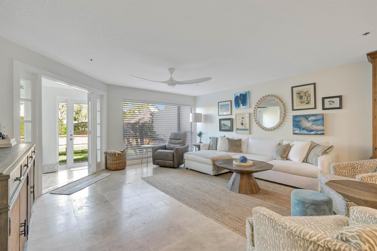 A bright living room features a white sectional, a round wooden coffee table, and tile flooring — 1000 N Us Highway 1 # 658, Jupiter FL 33477, JUPITER, FL