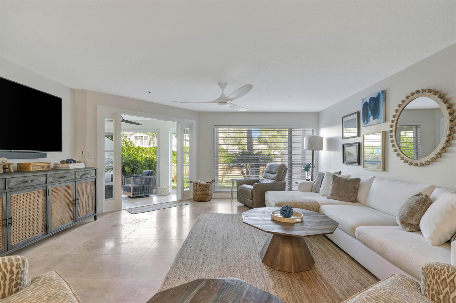 A living room features a white sectional sofa, a wooden coffee table, and patio access — 1000 N Us Highway 1 # 658, Jupiter FL 33477, JUPITER, FL