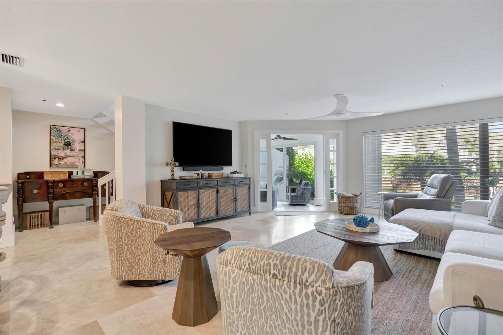 A living room features a large television, patterned armchairs, a white sofa, and tile flooring — 1000 N Us Highway 1 # 658, Jupiter FL 33477, JUPITER, FL