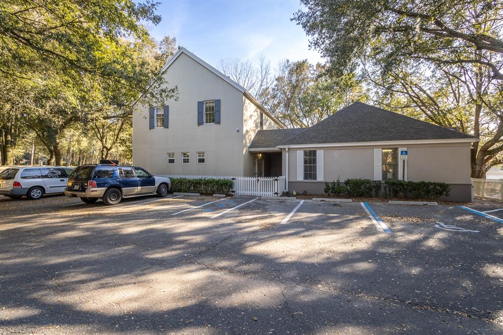 A two-story building with a parking lot in the foreground and surrounding trees — 5213 & 5217 & 5231 SW 91ST DRIVE, GAINESVILLE, FL