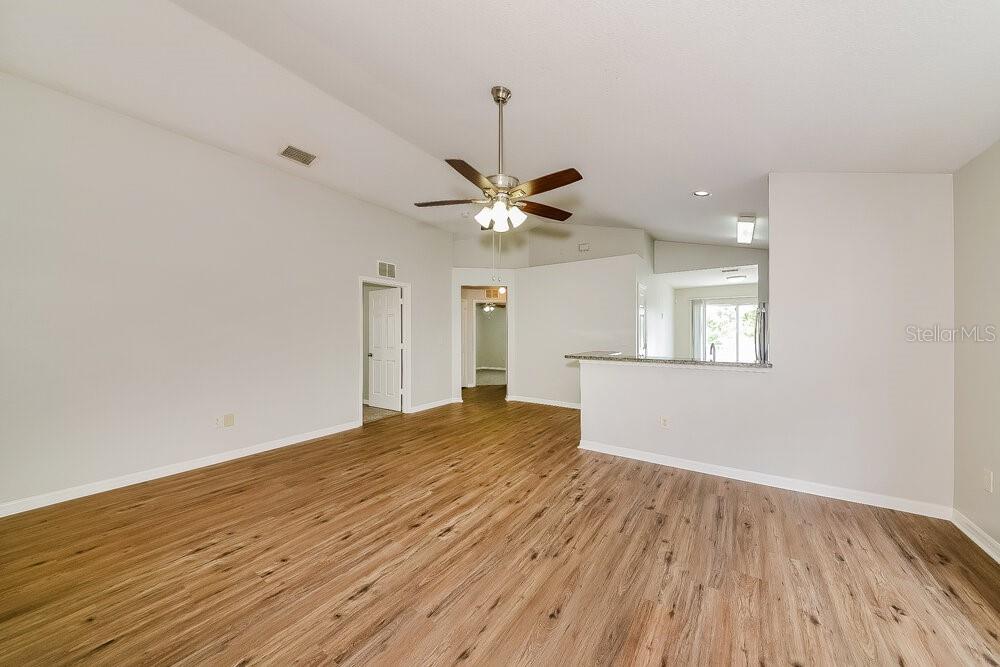 An empty living room features light wood-look flooring, a vaulted ceiling, and a ceiling fan — 727 CRISTELLE JEAN DRIVE, RUSKIN, FL