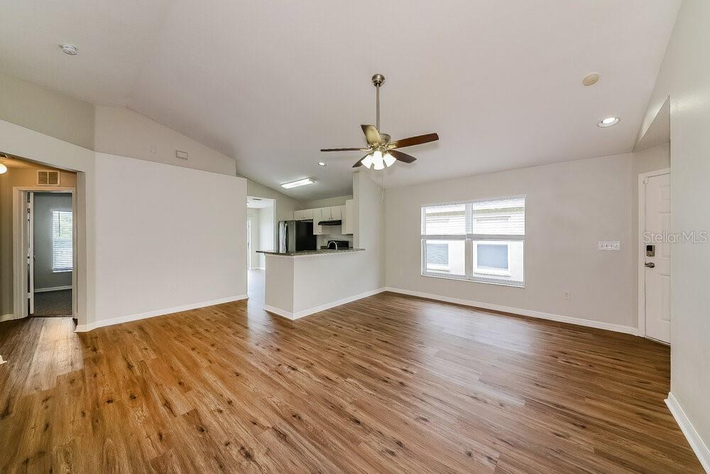 An open-concept living room features light wood-look flooring, a ceiling fan, and a kitchen pass-through — 727 CRISTELLE JEAN DRIVE, RUSKIN, FL