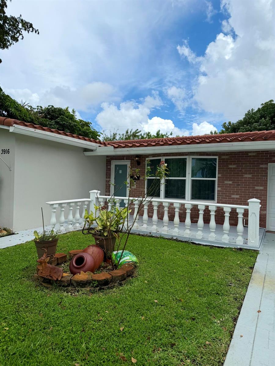 A single-story house features a red tile roof, brick facade, and a white balustrade porch — 3916 Adams Street, Hollywood FL 33021, HOLLYWOOD, FL