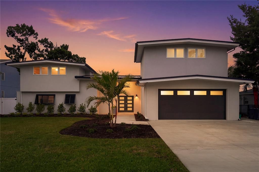 A two-story house with a gray exterior, a dark garage door, and a palm tree — 915 BAYSHORE DRIVE, TARPON SPRINGS, FL