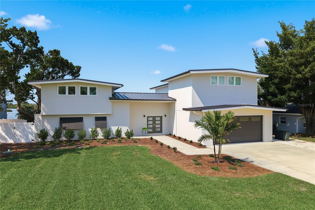 A two-story modern house with a white exterior, metal roof, and attached garage — 915 BAYSHORE DRIVE, TARPON SPRINGS, FL