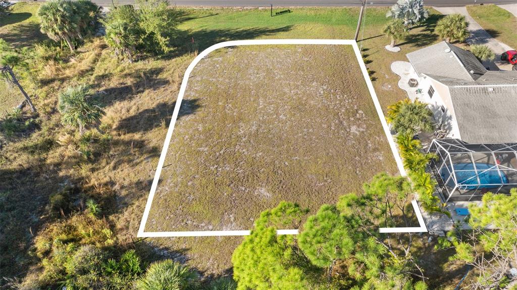 An aerial view shows a vacant, rectangular residential lot outlined in white next to a house — 6657 GASPARILLA PINES BOULEVARD, ENGLEWOOD, FL