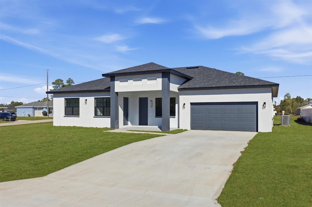 A single-story house with white stucco walls, a dark gray roof, and a two-car garage — 13218 SW 29TH CIRCLE, OCALA, FL