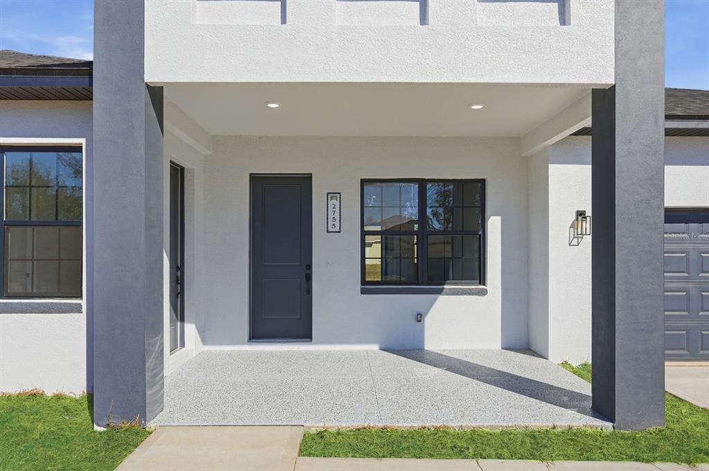A covered front porch with a gray door, window, and concrete flooring on a house — 13218 SW 29TH CIRCLE, OCALA, FL
