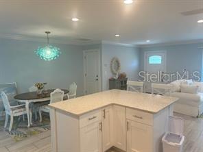 A kitchen island with a light countertop sits in front of a dining area — 196 OVERBROOK DRIVE E, LARGO, FL