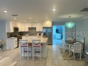 A kitchen with white cabinets and a center island opens into a dining area — 196 OVERBROOK DRIVE E, LARGO, FL