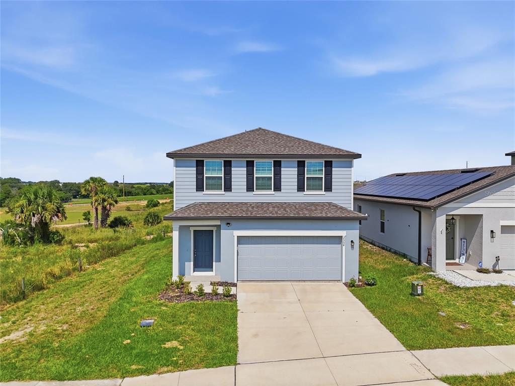 A two-story blue house with a gray garage and a concrete driveway sits on grass — 2504 PEONY PL, LAKE HAMILTON, FL