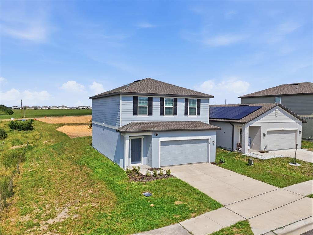 A two-story, light blue suburban house with a two-car garage and a concrete driveway — 2504 PEONY PL, LAKE HAMILTON, FL