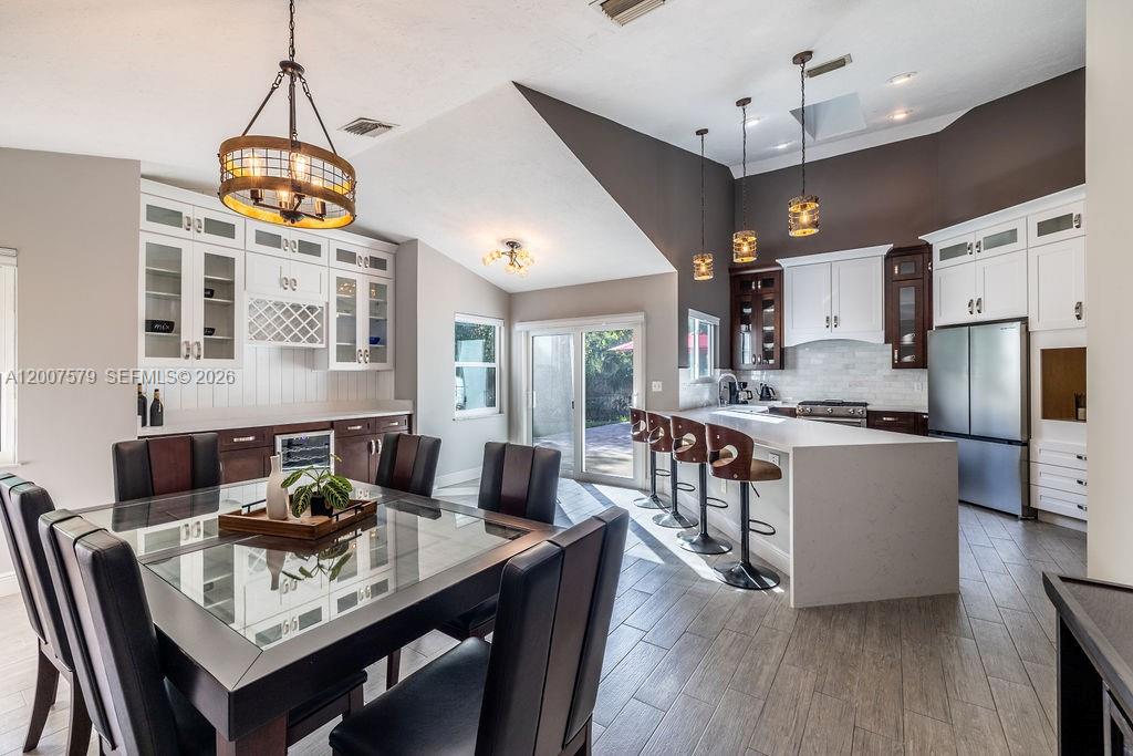 A modern kitchen and dining area features white cabinetry, a large island, and tile flooring — 9330 Seagrape Dr, Vero Beach FL 32963, VERO BEACH, FL