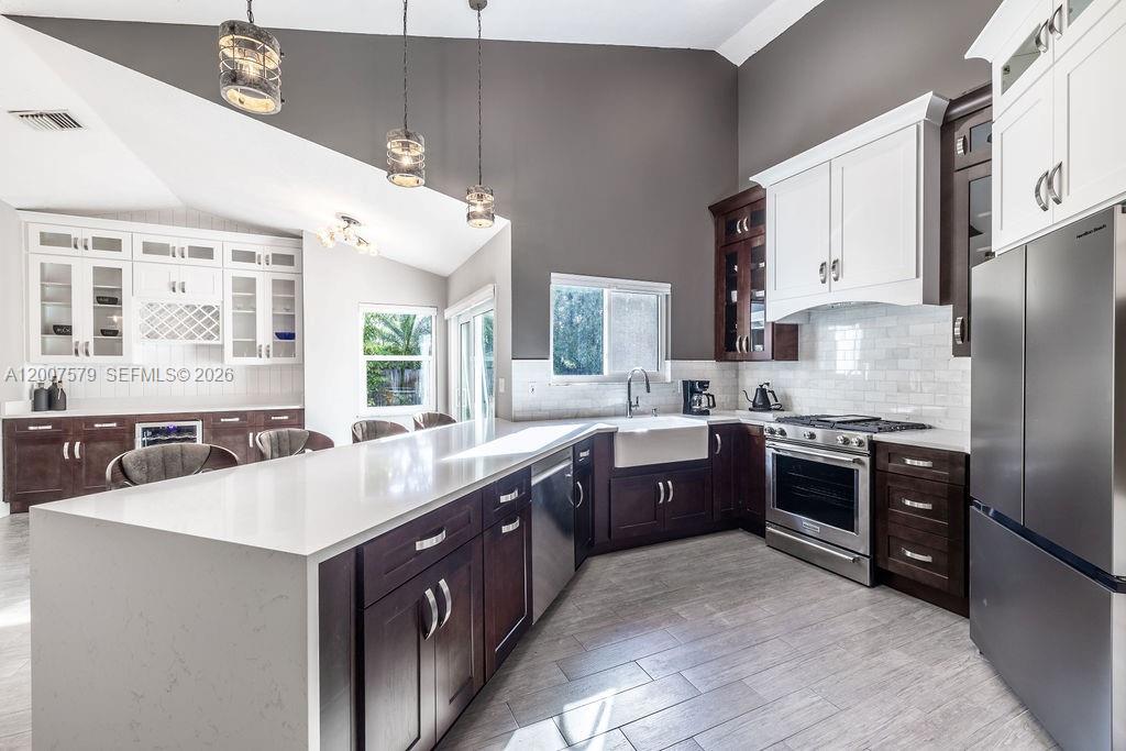A kitchen features dark wood cabinets, white countertops, stainless steel appliances, and a vaulted ceiling — 9330 Seagrape Dr, Vero Beach FL 32963, VERO BEACH, FL