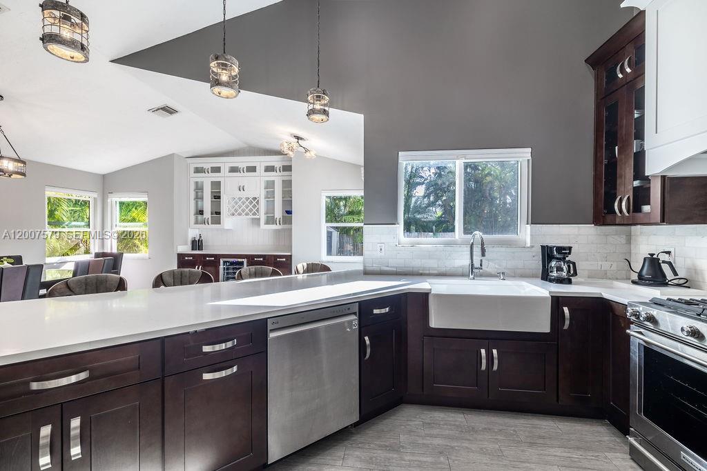 A modern kitchen features dark wood cabinets, white countertops, a farmhouse sink, and pendant lighting — 9330 Seagrape Dr, Vero Beach FL 32963, VERO BEACH, FL