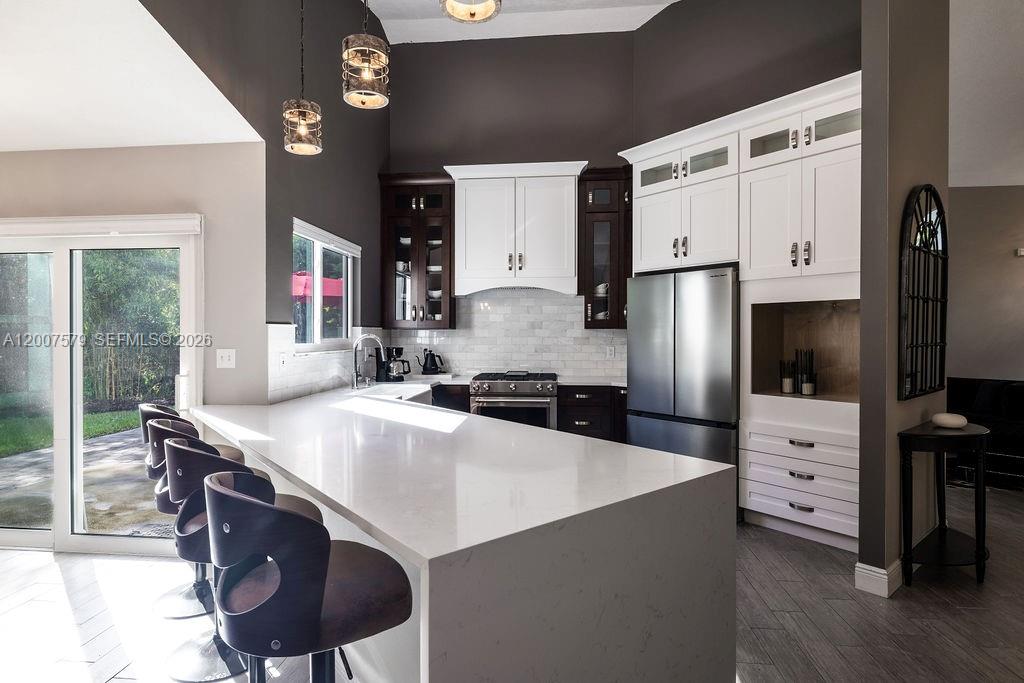 A modern kitchen features white and dark wood cabinetry, a quartz island, and stainless appliances — 9330 Seagrape Dr, Vero Beach FL 32963, VERO BEACH, FL