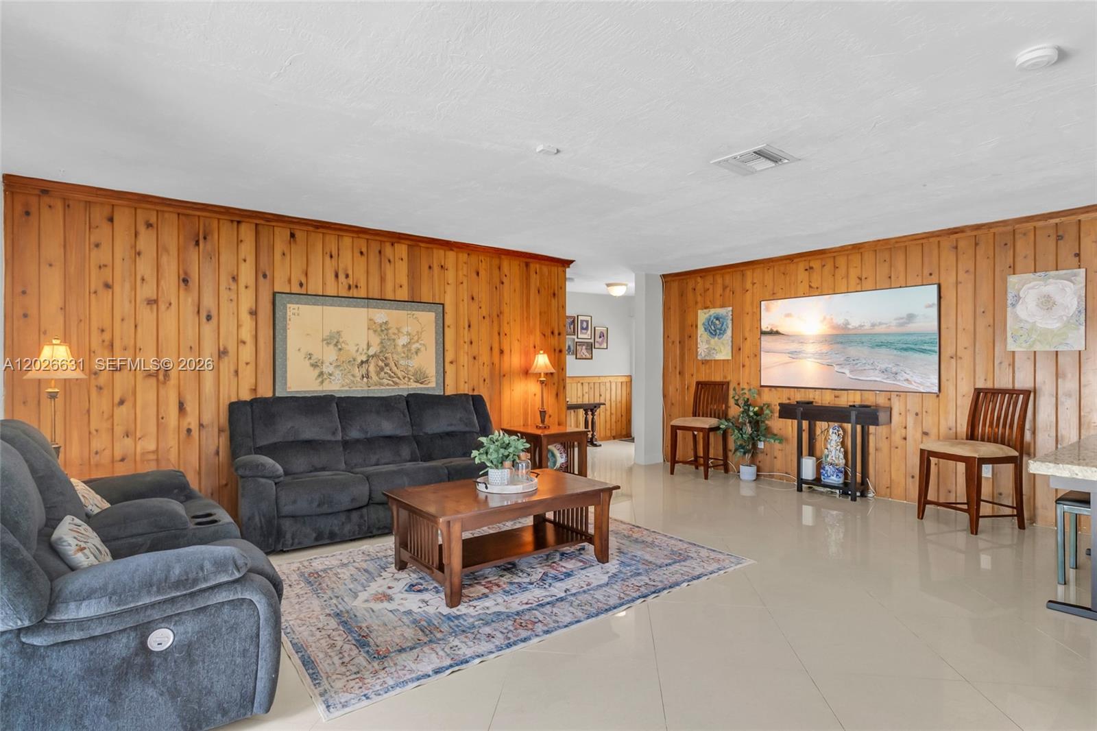 A living room features wood-paneled walls, a beige sofa, a coffee table, and a television — 18645 SW 90th Ave, Cutler Bay FL 33157, CUTLER BAY, FL