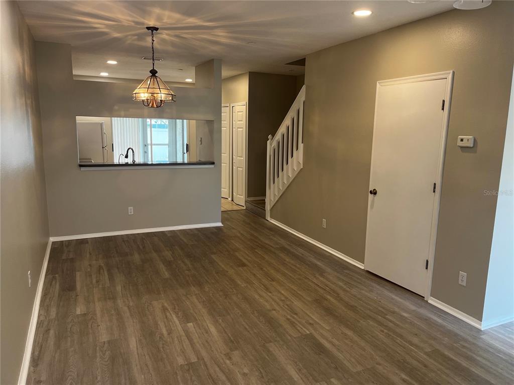 A dining area with wood-look flooring, a pass-through window to the kitchen, and a staircase — 331 COUNTRYSIDE KEY BOULEVARD, OLDSMAR, FL
