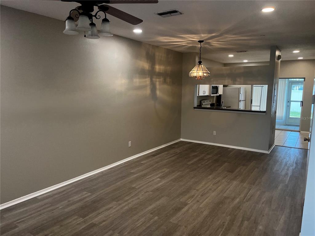 An open living area features gray walls, wood-look flooring, a ceiling fan, and a kitchen pass-through — 331 COUNTRYSIDE KEY BOULEVARD, OLDSMAR, FL
