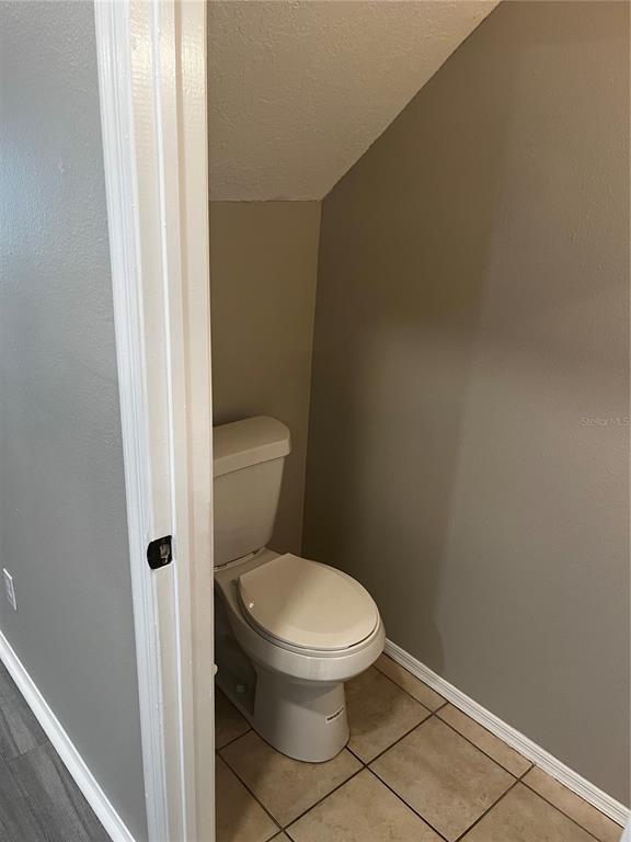 A small bathroom features a white toilet, beige tile flooring, and gray walls — 331 COUNTRYSIDE KEY BOULEVARD, OLDSMAR, FL