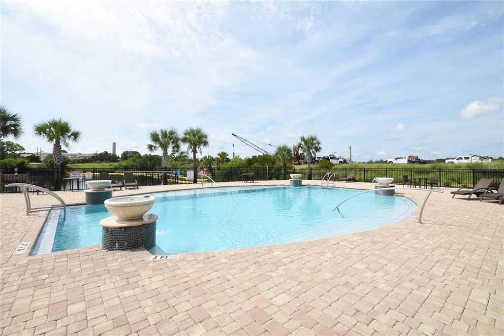 A swimming pool with a fountain and lounge chairs sits on a paved patio area — 114 DEL PALMA DRIVE, PALM COAST, FL