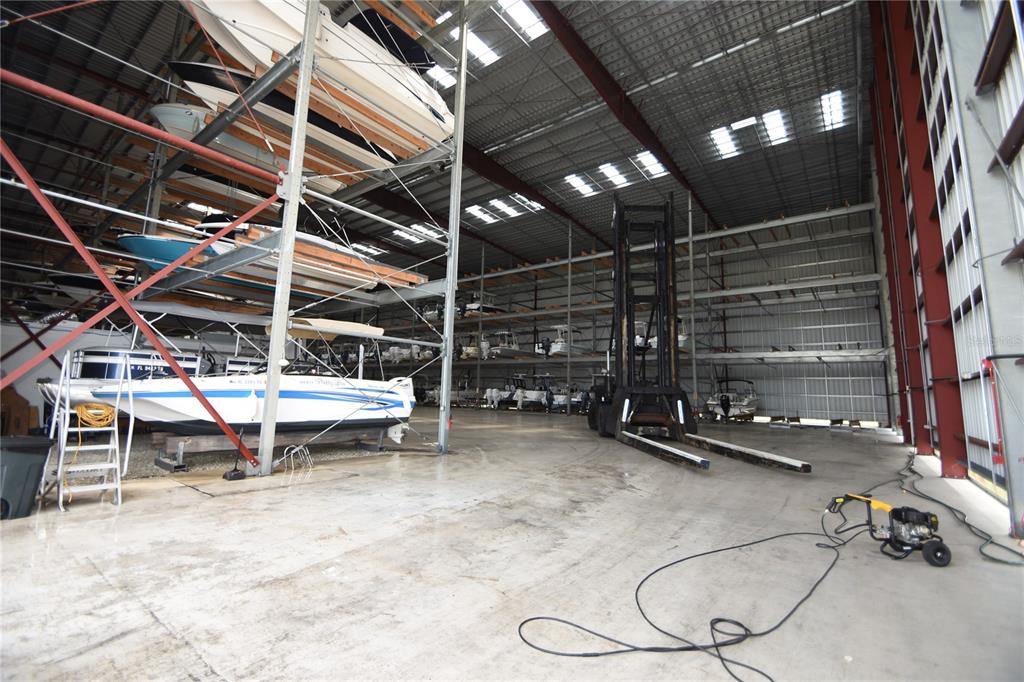 A large indoor boat storage facility with metal racks, a forklift, and concrete flooring — 114 DEL PALMA DRIVE, PALM COAST, FL