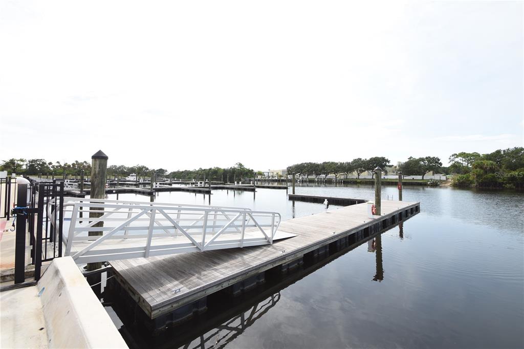 A wooden floating dock with a metal ramp extends into a calm marina — 114 DEL PALMA DRIVE, PALM COAST, FL