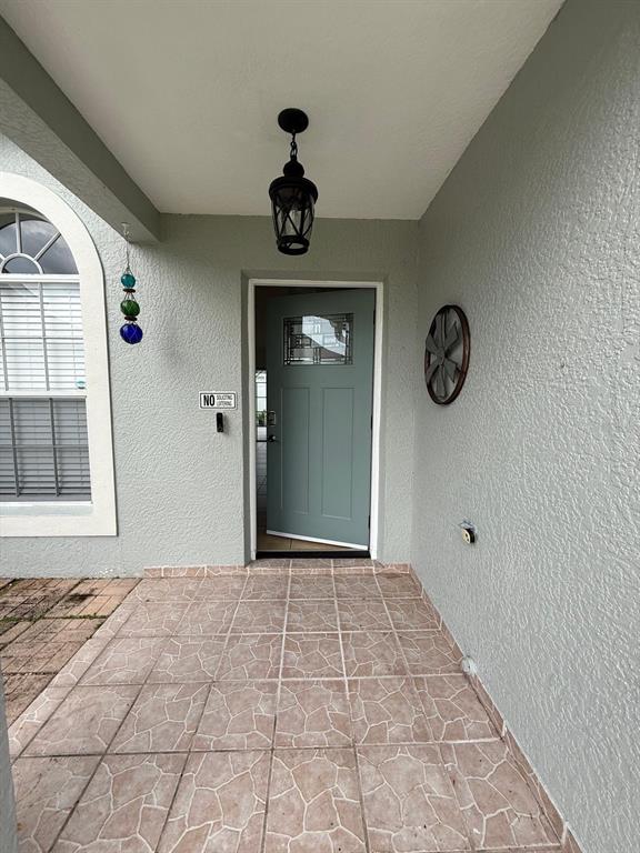 A covered entryway features a light blue front door, a hanging lantern, and tiled flooring — 2531 SAGE DRIVE, KISSIMMEE, FL