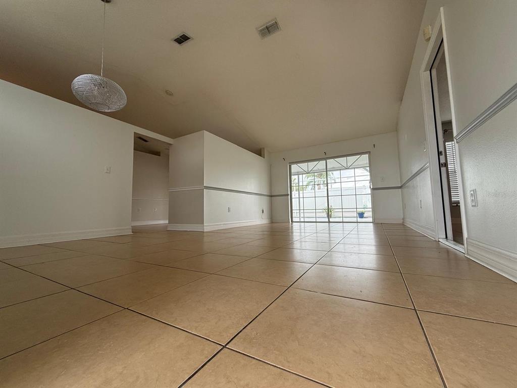 An empty room with beige tile flooring, white walls, and a sliding glass door — 2531 SAGE DRIVE, KISSIMMEE, FL