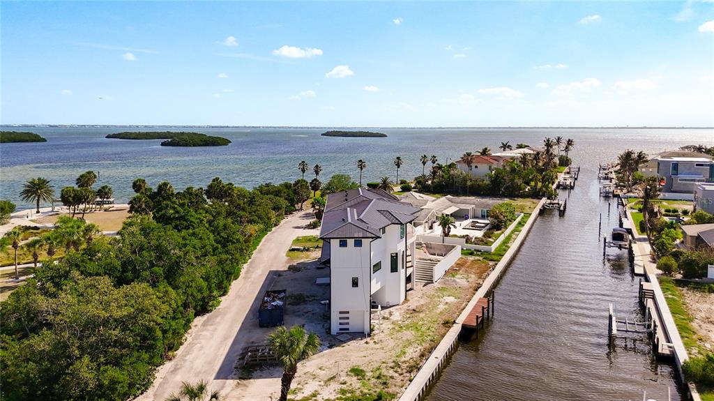 An aerial view shows a modern white house situated between a canal and dense vegetation — 530 JESSMYTH DRIVE, LONGBOAT KEY, FL