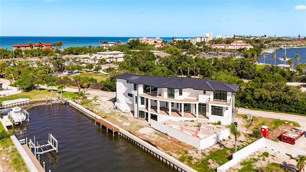 An aerial view shows a modern white house with a dark roof beside a canal — 530 JESSMYTH DRIVE, LONGBOAT KEY, FL